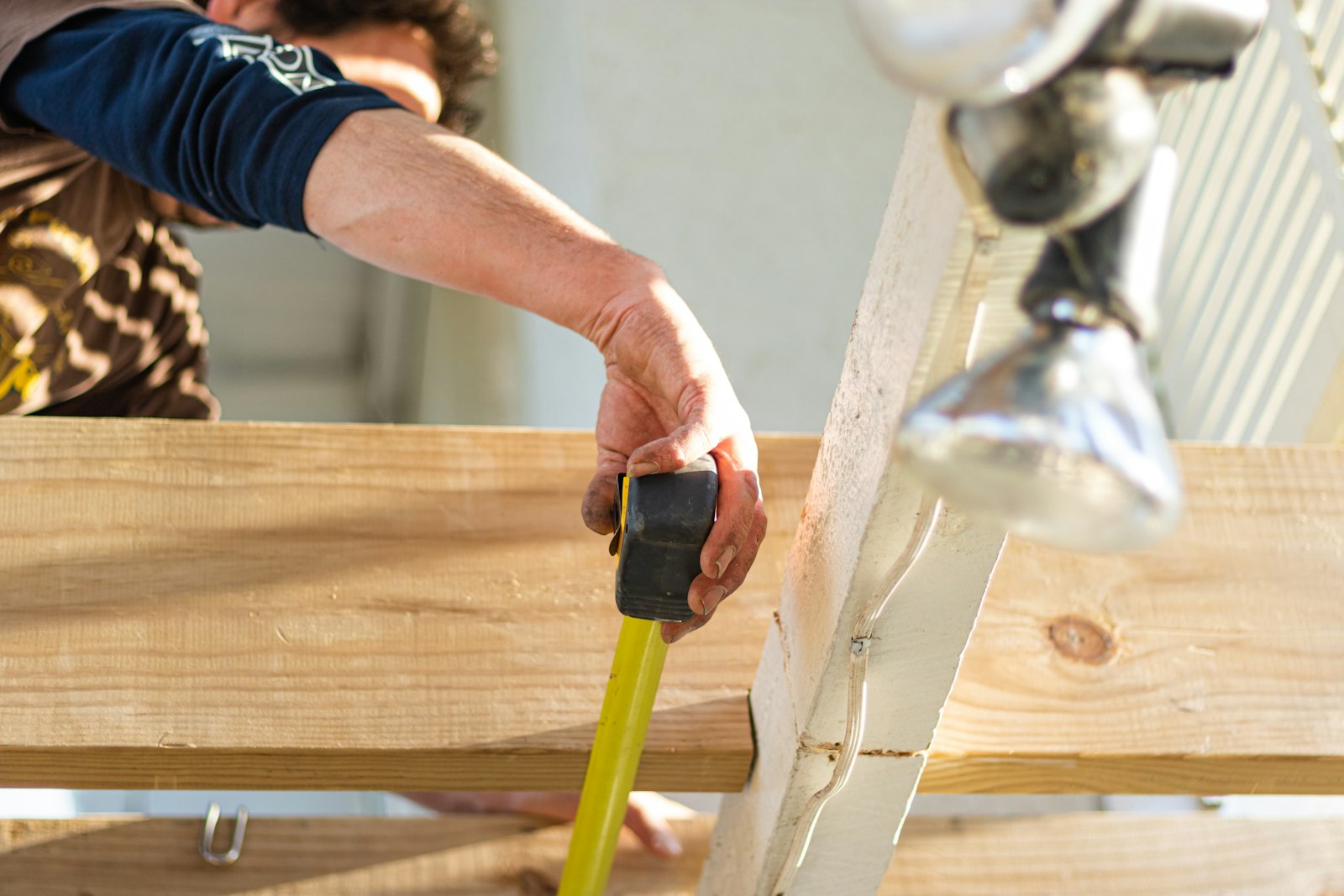 Carpenter measuring lumber with a tape measure on a CraftWell Group job in London Ontario